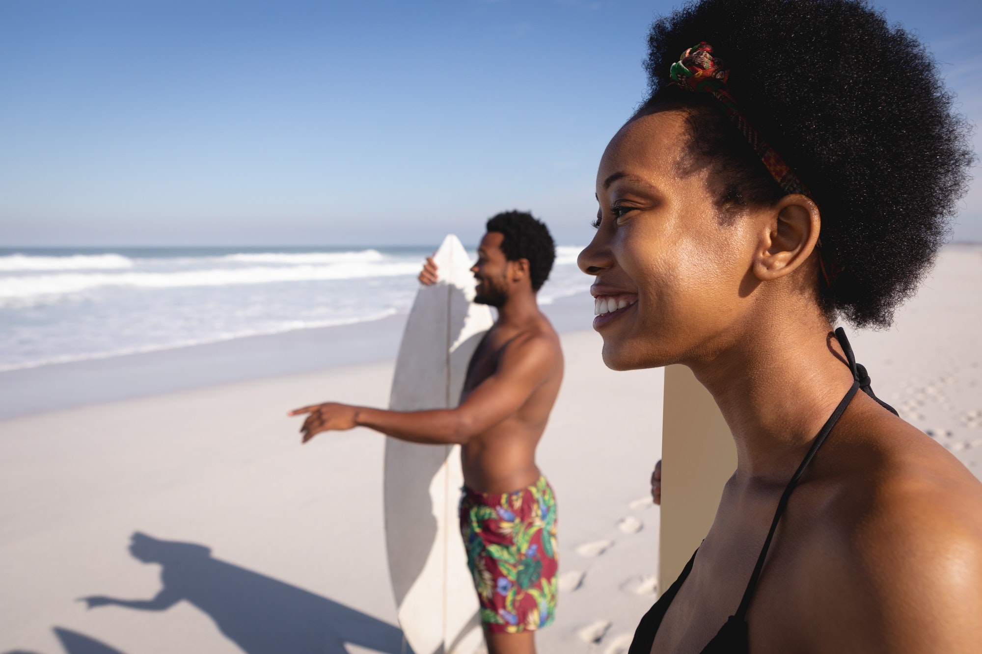 Young friends having fun on the beach in front of the sea with their surfboards